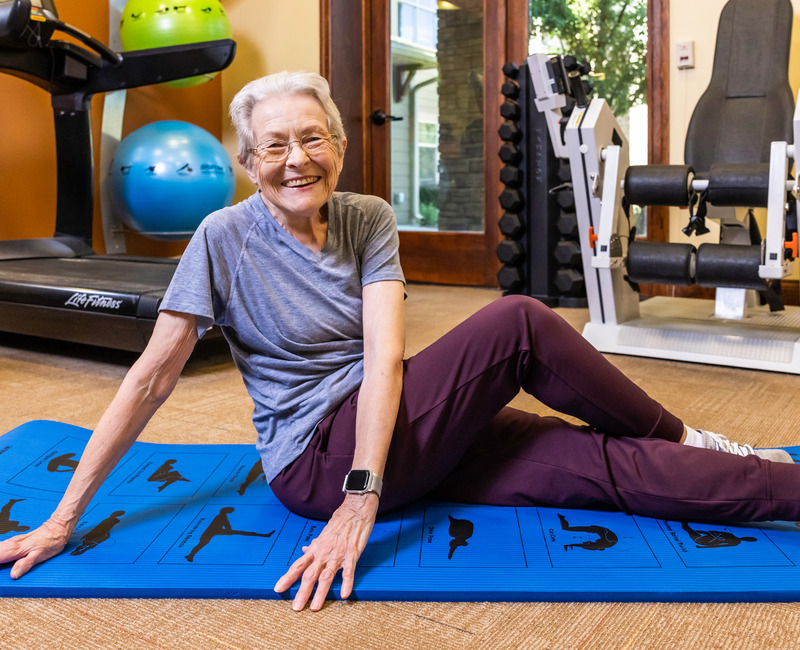 woman smiling and stretching on yoga mat